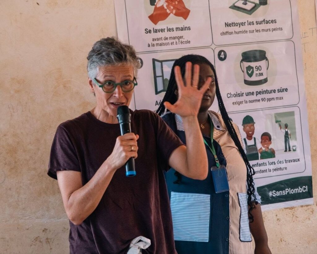 Une intervenante présente les gestes de prévention devant une affiche #SansPlombCI